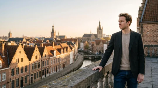 Vue panoramique d'une personne surplombant une ville belge au lever du jour, symbolisant une vision globale du patrimoine financier personnel.